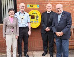 Father Denis along with our President Gary Blyth and other members at the presentation of the Defibrillator